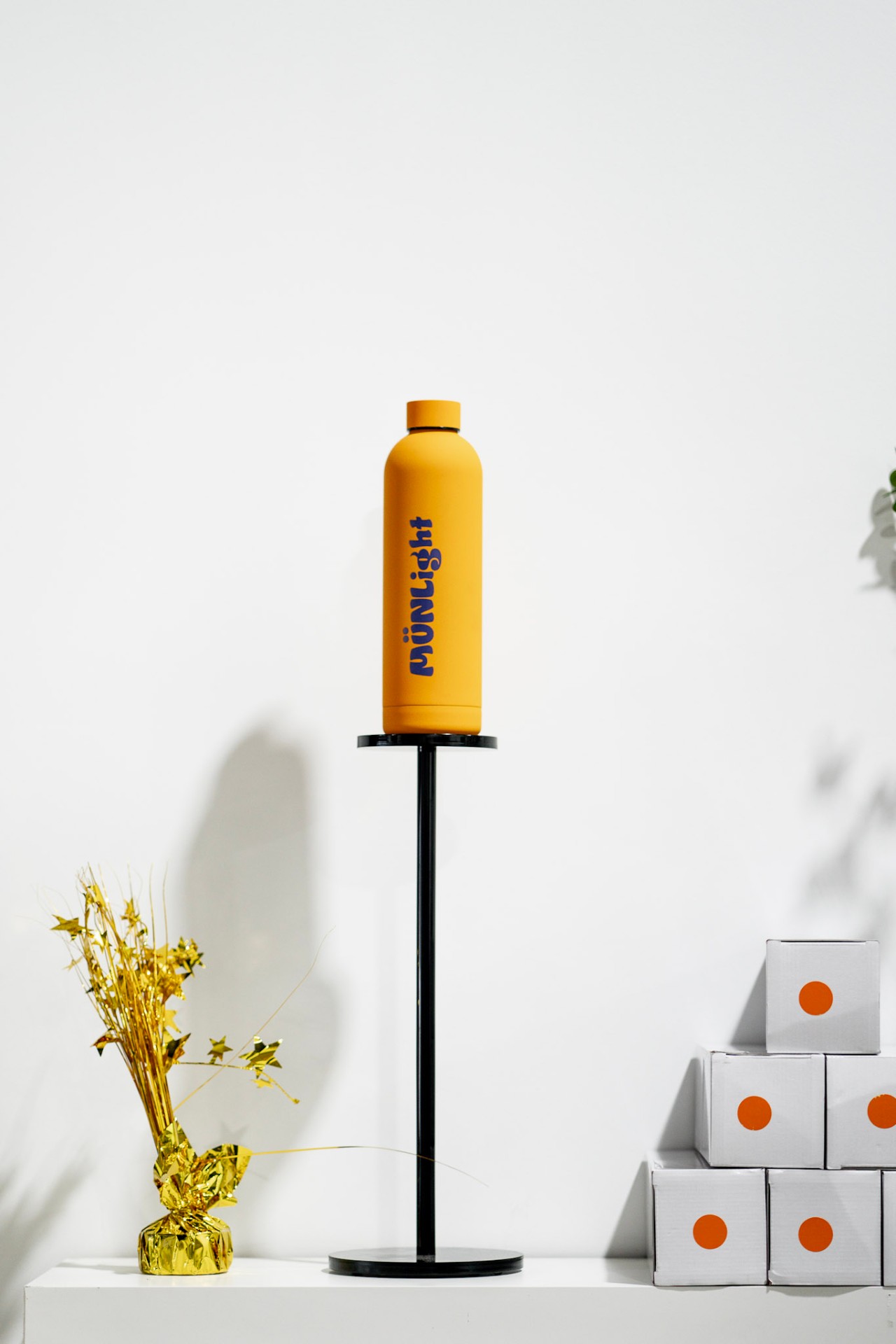 Münlight — orange bottle on pedestal